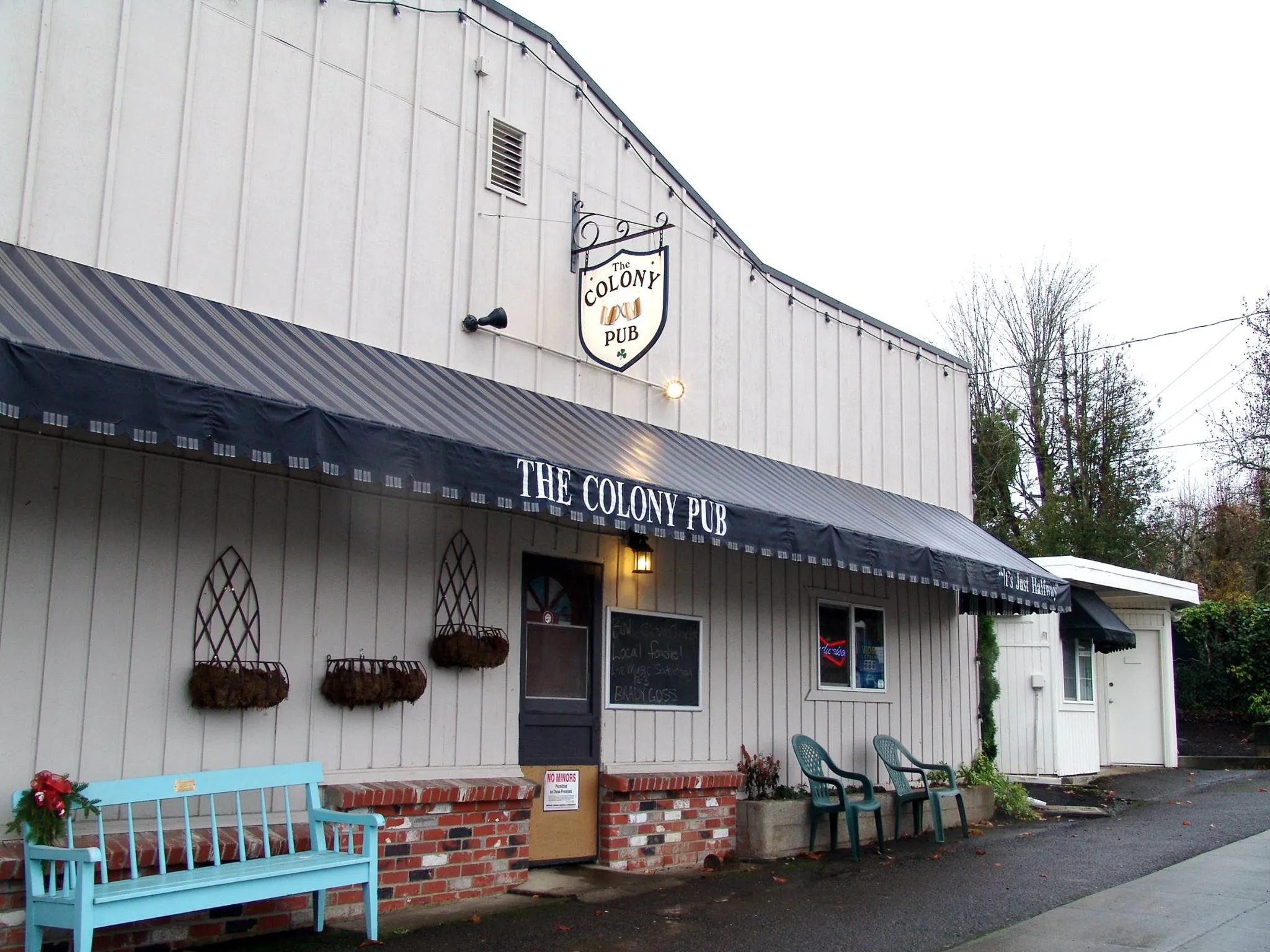 The pub in daylight — white wood-frame walls, black tin roof and the big roadside sign.