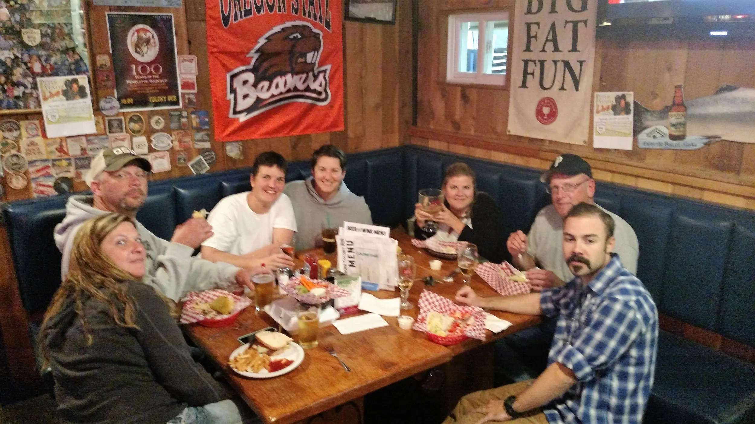 Booth seating along the back, wood paneling and vintage beer signs, six folks tucking into burgers.