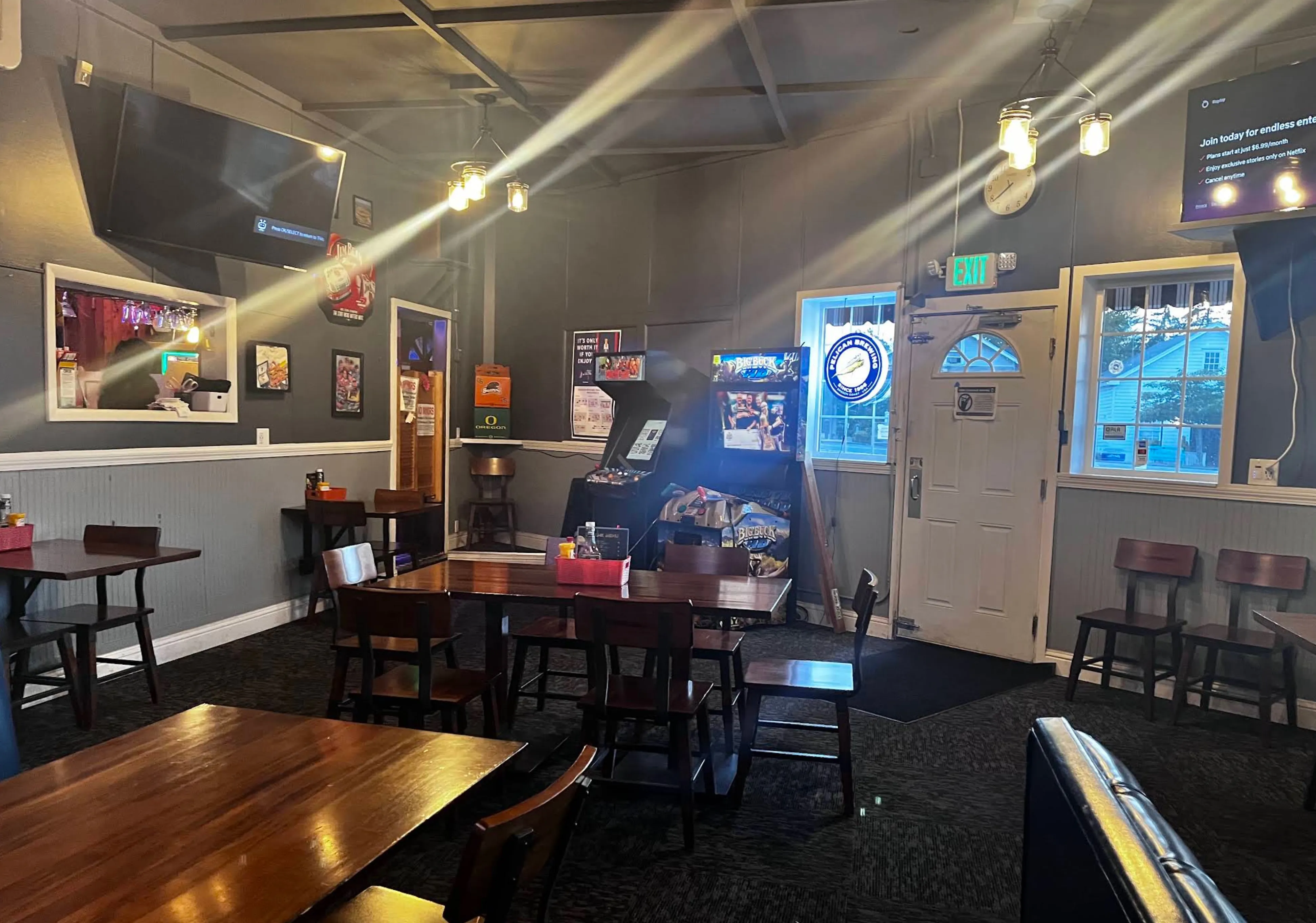 Afternoon light streaming across the dining room, an arcade cabinet and dartboard beside the sunburst-windowed door.